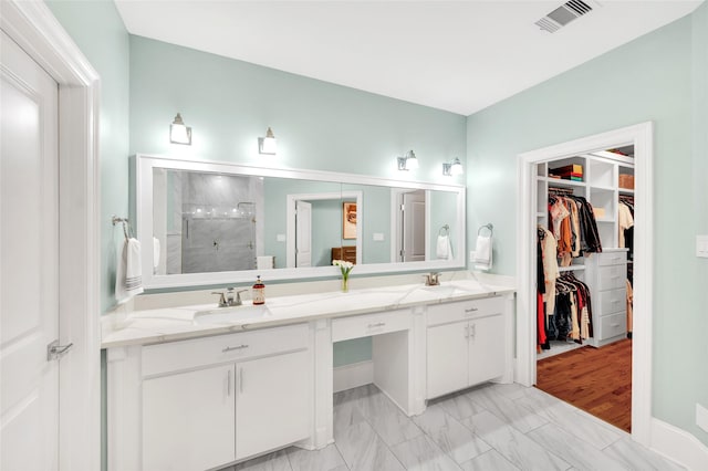 bathroom featuring a shower with door and vanity