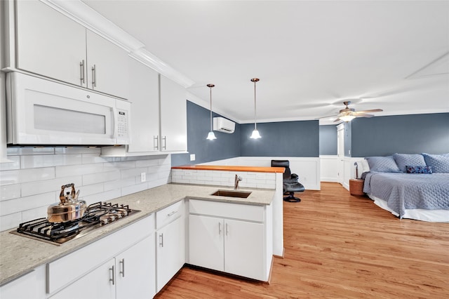 kitchen with kitchen peninsula, sink, white cabinetry, and hanging light fixtures