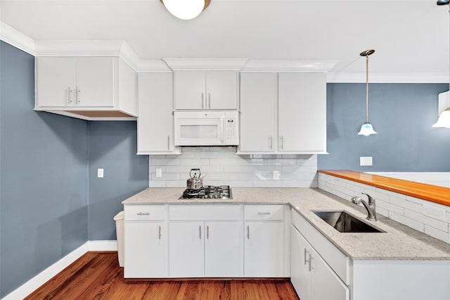 kitchen featuring pendant lighting, stainless steel gas stovetop, sink, backsplash, and white cabinetry