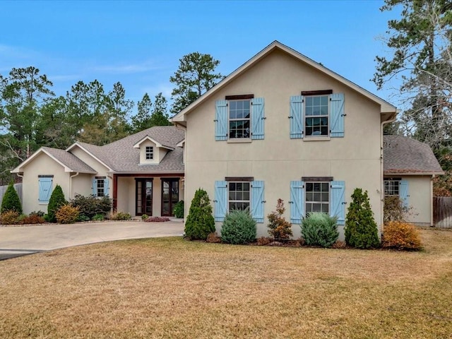 view of front of home with a front yard, roof with shingles, and stucco siding