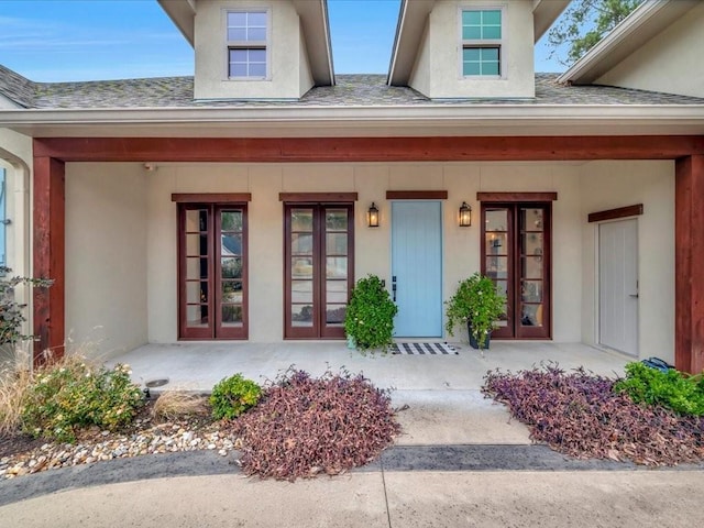 doorway to property featuring french doors, a shingled roof, and stucco siding