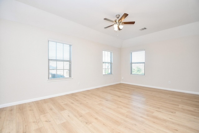 empty room with vaulted ceiling, ceiling fan, plenty of natural light, and light hardwood / wood-style floors