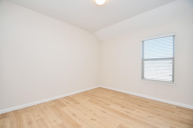 spare room featuring lofted ceiling and light wood-type flooring