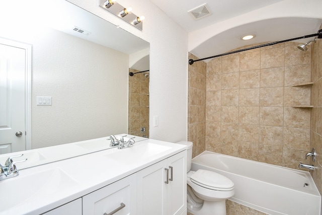 full bathroom with tiled shower / bath, vanity, and toilet