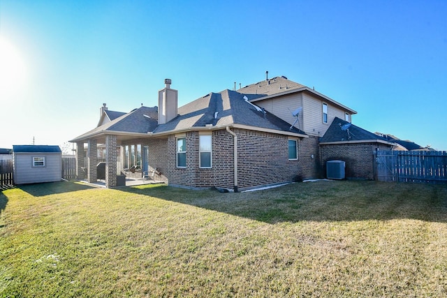 rear view of property featuring a patio, a lawn, central AC unit, and a storage unit