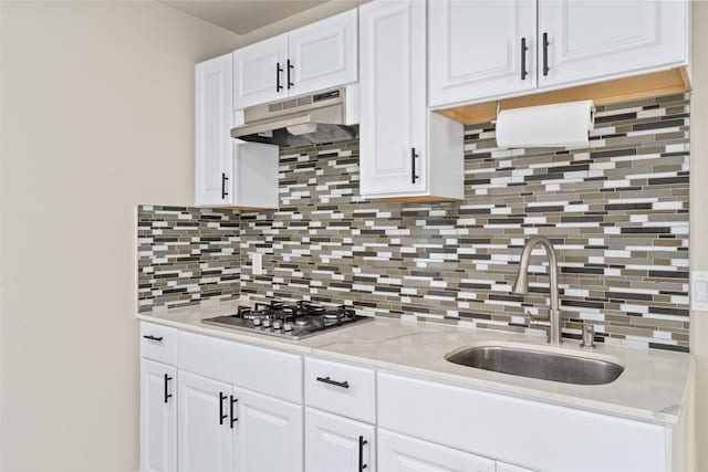 kitchen featuring stainless steel gas stovetop, white cabinets, tasteful backsplash, and sink