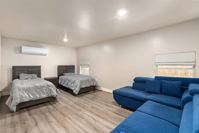 bedroom featuring a wall mounted AC and light hardwood / wood-style floors