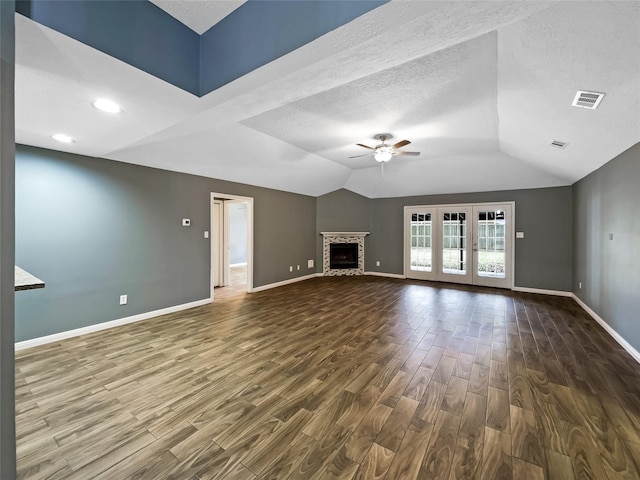 unfurnished living room featuring a stone fireplace, vaulted ceiling, ceiling fan, and dark hardwood / wood-style flooring