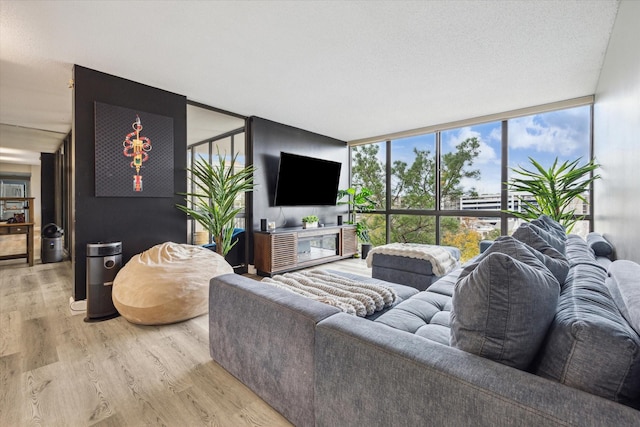 living room with a textured ceiling, plenty of natural light, a wall of windows, and light hardwood / wood-style flooring