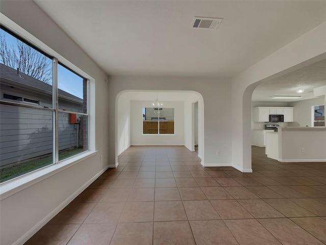 interior space with plenty of natural light, a notable chandelier, and light tile patterned flooring