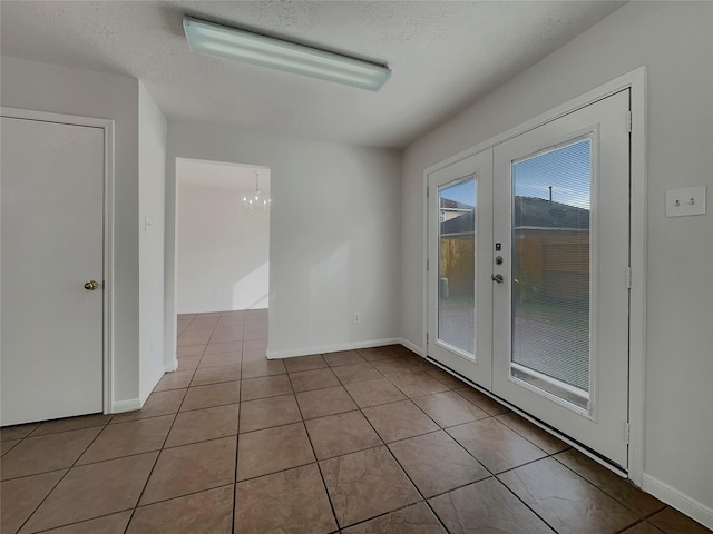 unfurnished room with a textured ceiling, light tile patterned floors, and french doors