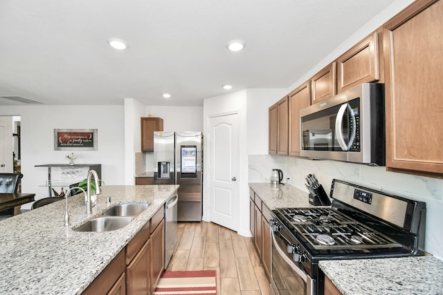 kitchen featuring light stone countertops, sink, backsplash, and appliances with stainless steel finishes