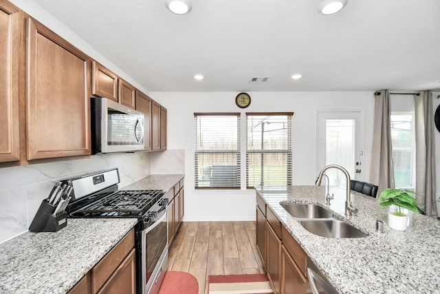 kitchen featuring light stone countertops, sink, stainless steel appliances, and light hardwood / wood-style floors