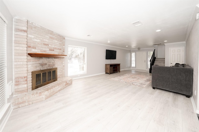 living room featuring a brick fireplace, crown molding, light hardwood / wood-style floors, and plenty of natural light