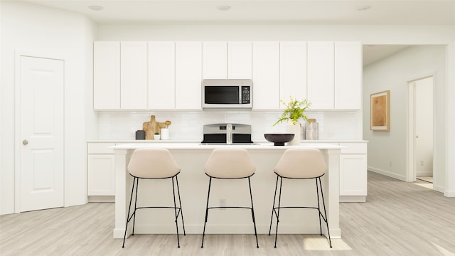 kitchen with white cabinetry, stove, and an island with sink