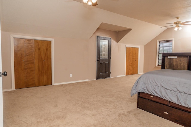 bedroom featuring vaulted ceiling, ceiling fan, two closets, and light colored carpet