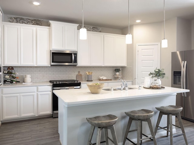 kitchen featuring white cabinetry, a kitchen island with sink, stainless steel appliances, and pendant lighting