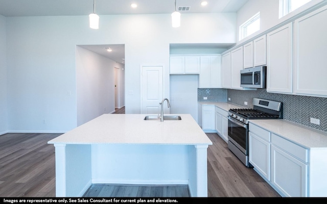 kitchen featuring sink, hanging light fixtures, stainless steel appliances, and a kitchen island with sink