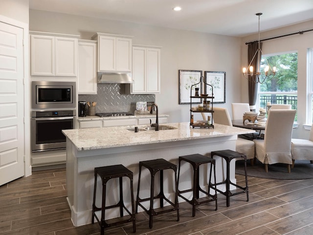 kitchen featuring sink, white cabinetry, hanging light fixtures, an island with sink, and stainless steel appliances