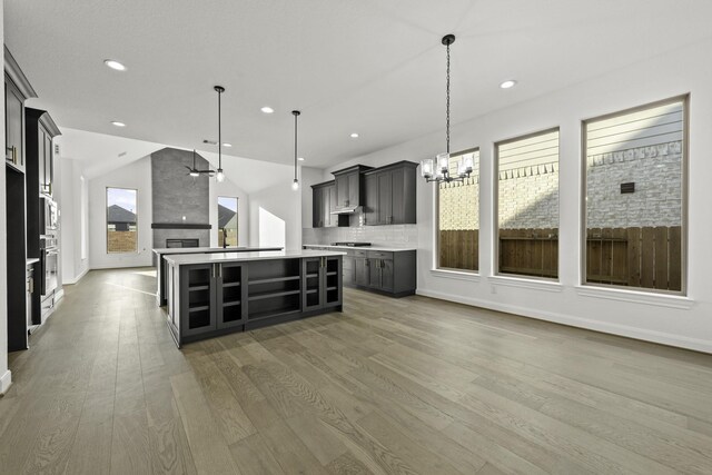 kitchen featuring tasteful backsplash, gray cabinets, hardwood / wood-style floors, a center island, and hanging light fixtures