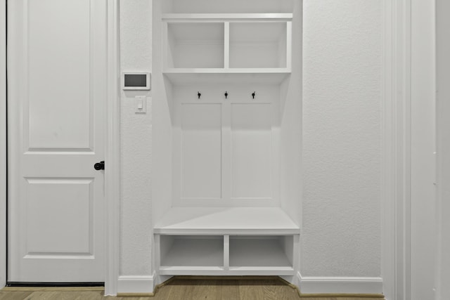 mudroom featuring a textured wall, baseboards, and wood finished floors