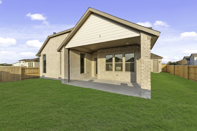 back of house with a yard, brick siding, a patio area, and a fenced backyard