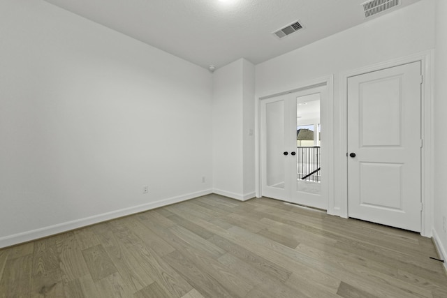 spare room with light wood finished floors, baseboards, and visible vents