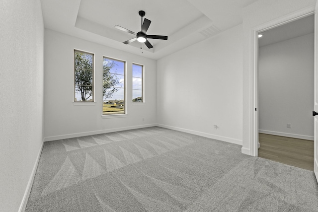 unfurnished room with ceiling fan, baseboards, a raised ceiling, and carpet flooring