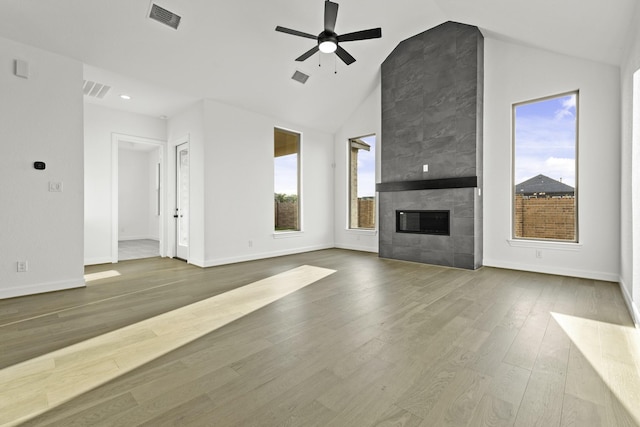 unfurnished living room featuring ceiling fan, wood finished floors, visible vents, baseboards, and a tiled fireplace