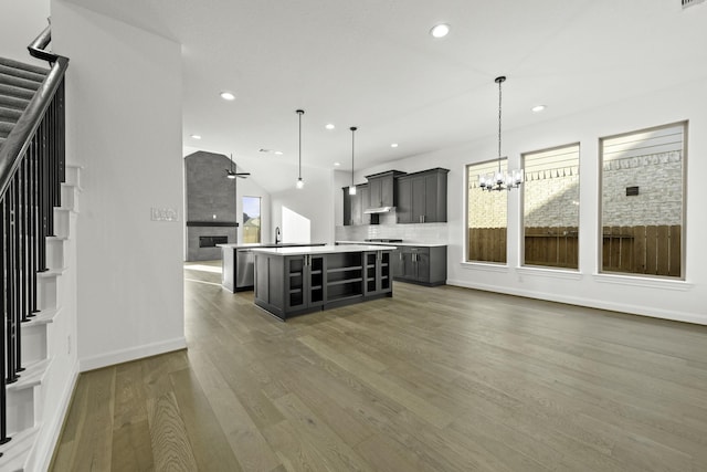 kitchen featuring a fireplace, wood finished floors, open floor plan, light countertops, and an island with sink