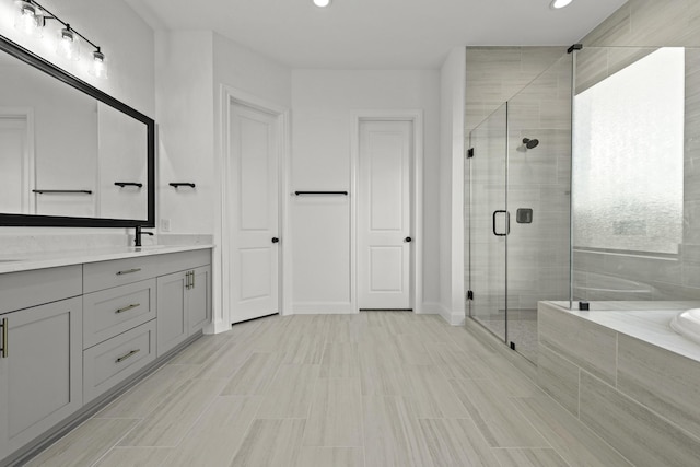 full bath with a stall shower, baseboards, vanity, a bath, and recessed lighting