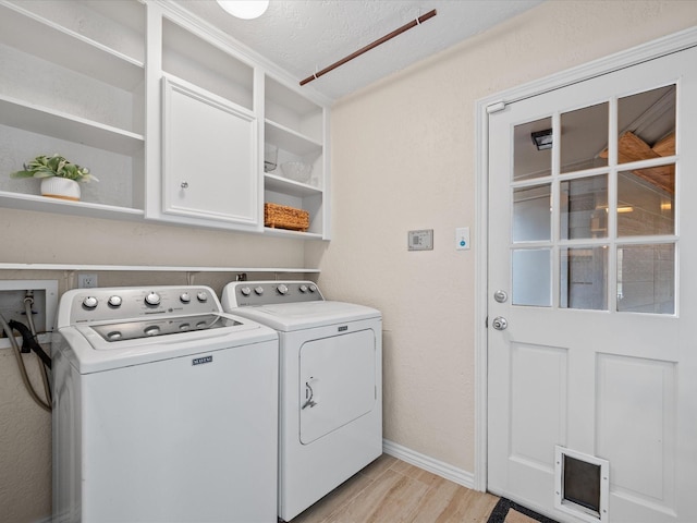 clothes washing area featuring cabinets, independent washer and dryer, and light hardwood / wood-style flooring