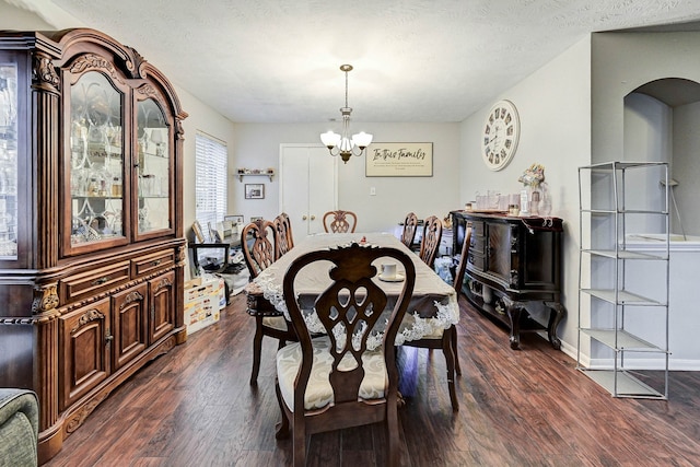 dining space with a textured ceiling, dark hardwood / wood-style floors, and a notable chandelier