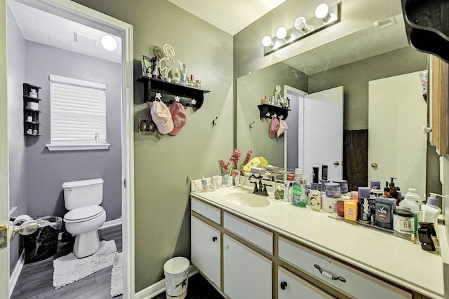 bathroom with toilet, vanity, and hardwood / wood-style floors