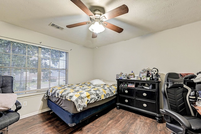 bedroom featuring dark wood-type flooring, ceiling fan, and a textured ceiling