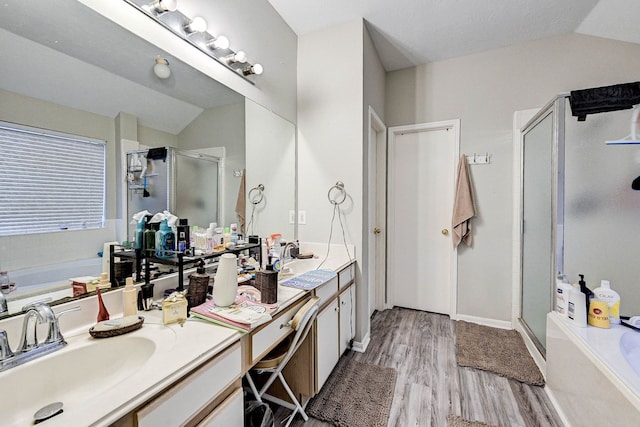 bathroom featuring wood-type flooring, vaulted ceiling, vanity, and shower with separate bathtub