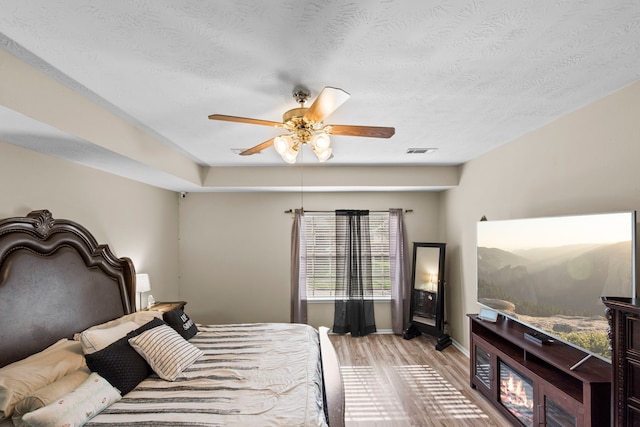 1711 Village Court Ln, Rosenberg, TX 77471 - bedroom with a textured ceiling, light wood-type flooring, baseboards, visible vents, and a ceiling fan