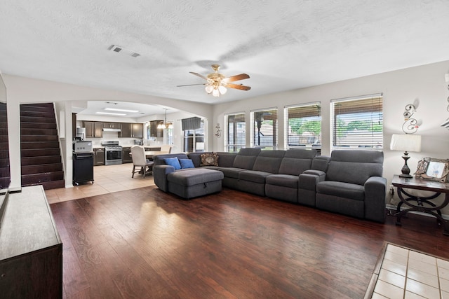 1711 Village Court Ln, Rosenberg, TX 77471 - living room featuring visible vents, a ceiling fan, arched walkways, light wood-type flooring, and stairs