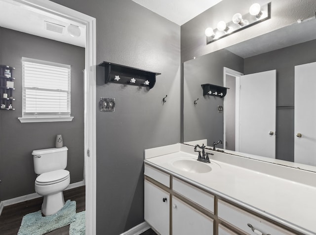 1711 Village Court Ln, Rosenberg, TX 77471 - bathroom featuring toilet, visible vents, baseboards, wood finished floors, and vanity