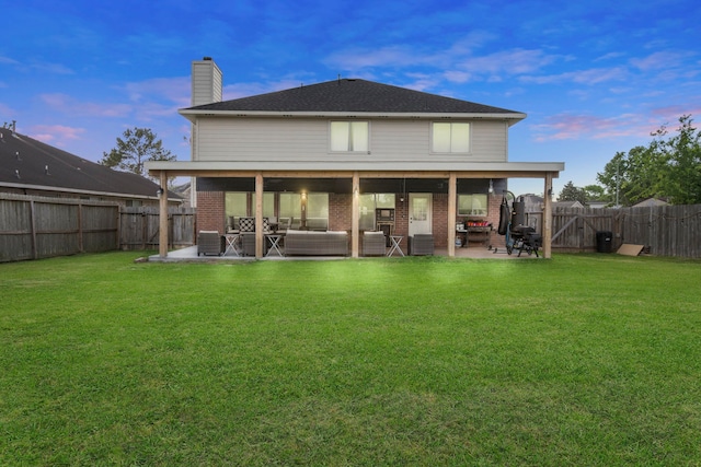 1711 Village Court Ln, Rosenberg, TX 77471 - back of property at dusk with brick siding, a patio area, a lawn, and a fenced backyard