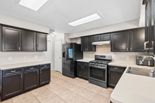 1711 Village Court Ln, Rosenberg, TX 77471 - kitchen featuring a sink, light countertops, under cabinet range hood, black fridge, and gas stove