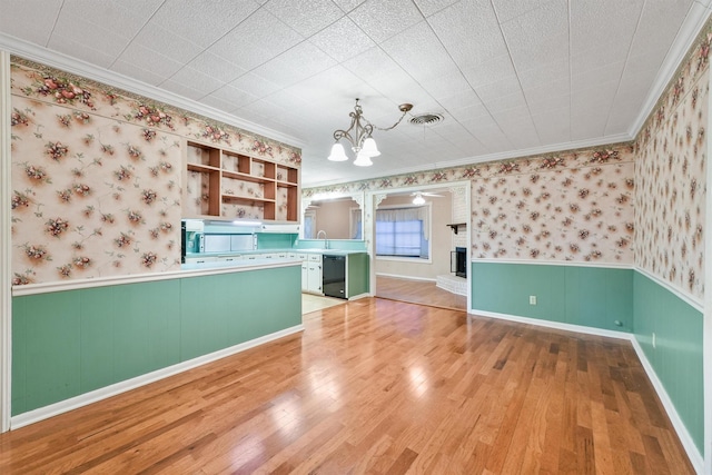 kitchen featuring a notable chandelier, wood-type flooring, pendant lighting, green cabinetry, and crown molding