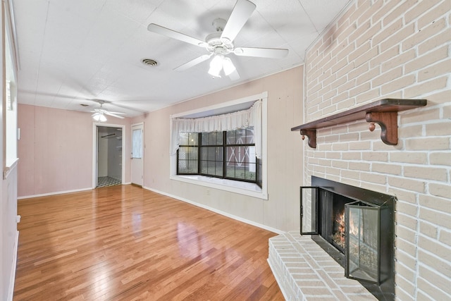 unfurnished living room with ceiling fan, a fireplace, and wood-type flooring