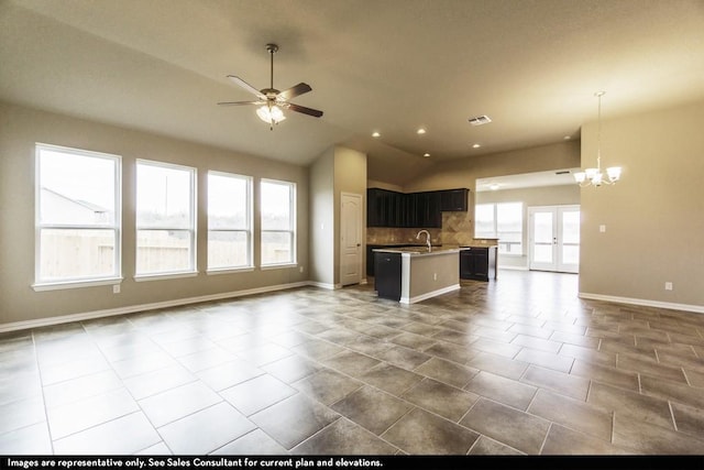 kitchen with backsplash, vaulted ceiling, sink, an island with sink, and ceiling fan with notable chandelier