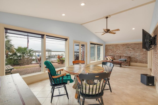 tiled dining area featuring ceiling fan, brick wall, and lofted ceiling