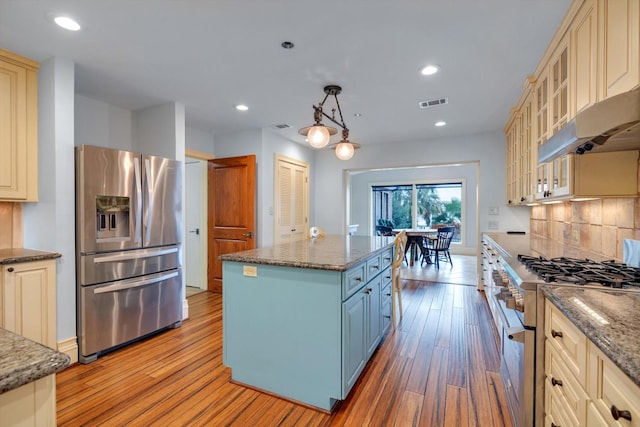 kitchen featuring dark stone counters, appliances with stainless steel finishes, hanging light fixtures, and a kitchen island