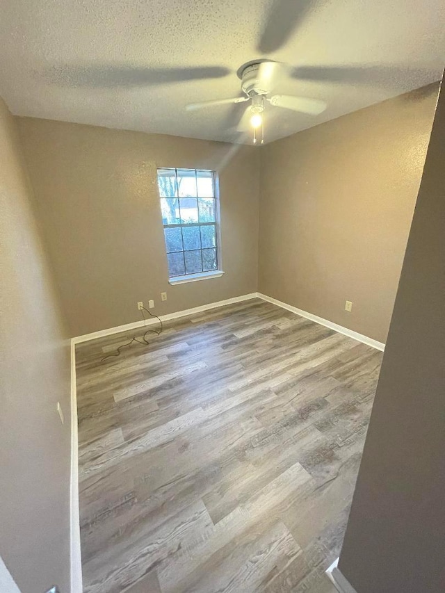 empty room with ceiling fan, a textured ceiling, and hardwood / wood-style floors