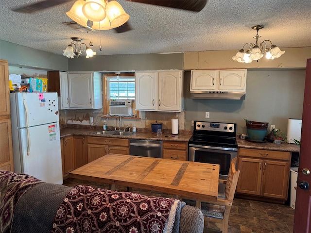 kitchen with a textured ceiling, cooling unit, stainless steel appliances, sink, and hanging light fixtures