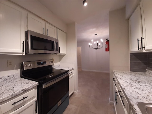 kitchen with an inviting chandelier, stainless steel appliances, hanging light fixtures, light stone countertops, and white cabinets