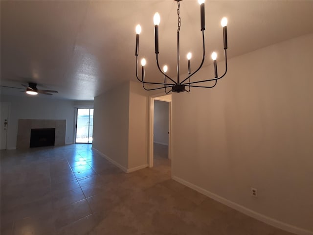 interior space with ceiling fan with notable chandelier and a tile fireplace